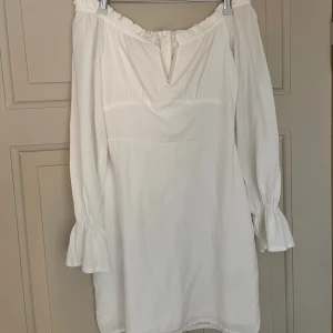 Vit klänning - Figurnära vit klänning som är offshoulder och har en lång puffärm. Perfekt till student/konfirmation! Använd vid endast ett tillfälle så i mycket bra skick. 