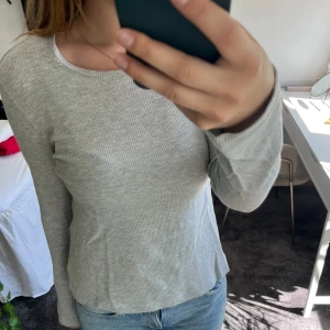 Grå långärmad tröja - Skön grå långärmad tröja som inte kommer till användning längre. Har ett litet hål vid sidan vilket man kan se i sista bilden🫶