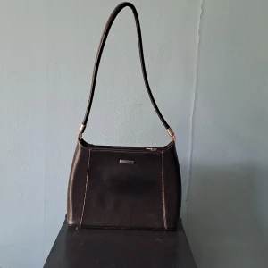 Svart y2k handväska med silvar detaljer - Svart y2k handväska med silvar detaljer. 27cm vidg 18,5cm bred 7cm jup 