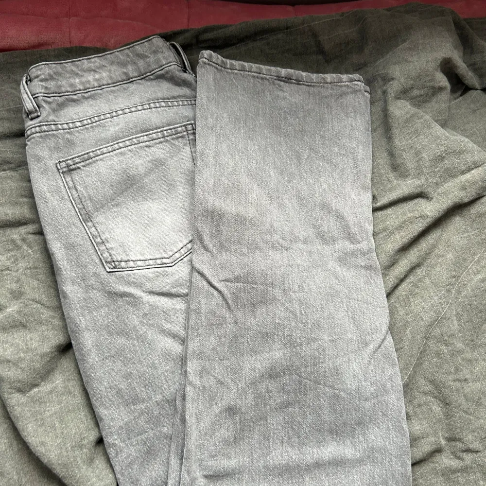 Ett par lågmidjade grå jeansbyxor av märket lager 157. Byxorna har en klassisk femficksdesign med knappar och dragkedja i gylfen. De är tillverkade i ett slitstarkt material och har en rak passform.. Jeans & Byxor.