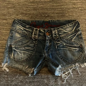 Snygga jeansshorts från Pepe Jeans - Säljer vidare ett par coola jeansshorts från Pepe Jeans i storlek W29. Då de var för stora! De är blå med en sliten look och fransiga kanter. Perfekta för sommaren! 💙 (bilder från tidigare säljaren)
