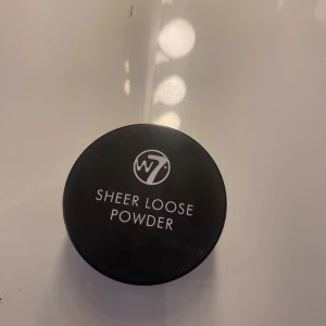 Sheer Loose Powder från W7 - Säljer ett Sheer Loose Powder från W7. Det är ett löspuder som kommer i en rund, genomskinlig burk med svart lock. Perfekt för att sätta din foundation och ge en matt finish. Pudret är i en ljus beige färg och är lätt att applicera för en naturlig look.