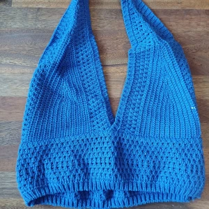 Blå stickad halterneck topp - En superfin mörkblå stickad halterneck topp. Ärmlös med djup v-ringning. Perfekt för sommaren och kan användas både till vardags och fest. Toppen är i nyskick och passar bra till jeans eller kjol!