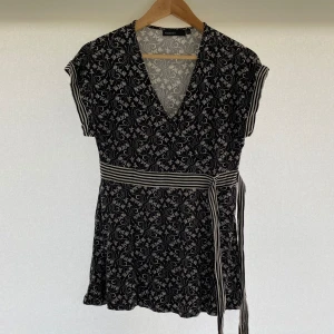 KappAhl Tunika - En svart tunika från KappAhl. Tunikan har korta ärmar och ett knytband i midjan med svartvita ränder. Använd 1 gång. Storlek: M. Hör av er vid eventuella frågor!!