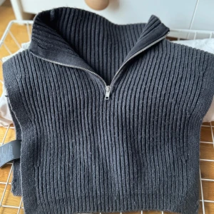 Mörkgrå ribbad tröja med dragkedja - Säljer en snygg mörkgrå ribbad tröja med dragkedja som kan ha under hoodies eller kofta. Perfekt för höst och vinter, den är både stilren och varm. Tröjan har en hög krage som kan justeras med dragkedjan. Materialet är mjukt och bekvämt, vilket gör den idealisk för kalla dagar. Passar bra till både vardag och lite finare tillfällen.