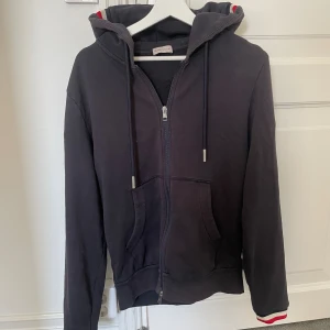 Moncler maglia zip hoodie - Moncler hoodie i väldigt bra skick. Självklart äkta (bevis finns). Det är storlek L men är lite liten i storleken och passar mer som M. Nypris är ungefär 5000kr. Skriv vid frågor och annat.