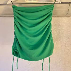 Grön kort kjol från Zara med schrunchi detaljer och snören nedtill. Försluts med dragkedja baktill. Använd en gång.