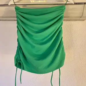 Grön kort kjol från Zara med schrunchi detaljer och snören nedtill. Försluts med dragkedja baktill. Använd en gång.