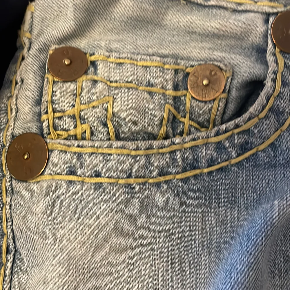 Ett par jättesnygga vitange true religon jeans i ljusblå färg med gula trådar. Jeansen är i jättebra skick och säljer för att dom inte kommer till användning (pris kan diskuteras). Jeans & Byxor.