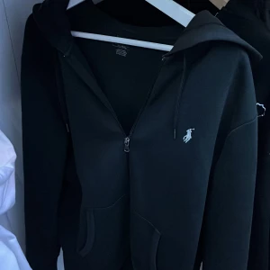 Ralph lauren hoodie svart - Säljer min Ralph lauren hoodie för att ja inte gillar den längre, den har tappat sin färg lite gran men är fof bra skick, har några små hål på höger arm men de syns inte om man inte kollar skit nära kom med förslag på pris gärna 