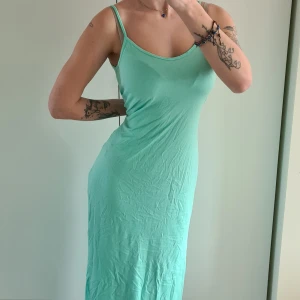 Figurnära klänning  - En figurnära klänning i turkos. Helt oanvänd, prislapp finns kvar. Skön klänning men lite stor i storleken om man vill att den sitter tight. Kom med prisförslag😊  Material: 50% Modal, 50% Ekologisk Bomull.
