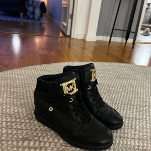 Michael kors skor - Svarta Michael kors sneakers med kilklack. Guldig logga. Väldigt bra skick, knappt använda. Storlek 38. Kan skickas om köpare betalar frakt.  Säljs för 400kr