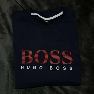 HUGO BOSS LÅNGÄRMAD - Långärmad mörk blå Hugo boss med röda detaljer. Ny, beställde fel storlek inte haft tid att returnera. Säljer billigt!