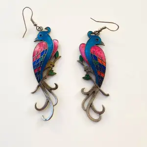 Färgglada örhängen föreställande fåglar  Okänd metall 