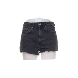 Svarta jeansshorts - Ett par svarta jeansshorts med hög midja och råa kanter. Shortsen har fem fickor och en knapp- och dragkedjestängning framtill.