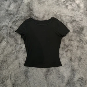 T-Shirt - En helt svart tshirt från Shein, i stl XS. Den sitter tajt och är mjuk