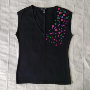 Svart v-ringad topp med paljetter 🖤 - Svart v-ringad, mjuk och stretchig topp. Med färgglada "paljetter". I fint skick. Storlek 36/38