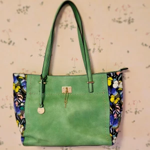 Fjärilsväska - Säljer en väska som är lite sliten på utsidan. Syns inte så mycket. Stort utrymme med fack på insidan. Ett fack ute. Mellan 30 och 40cm lång. Möts i Göteborg. 250kr. Står susen på den.