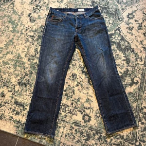 Blå jeansbyxor från Boss - Ett par blå jeansbyxor från Boss med klassisk femficksdesign och en läderetikett med Boss-logotypen på baksidan. Byxorna har en rak passform och är tillverkade i denim.