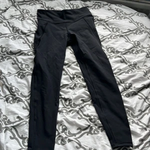 Svarta leggings från Reebok - Ett par svarta leggings från Reebok med Speedwick-teknologi. De har en hög midja och är tillverkade i ett syntetmaterial som är designat för att transportera bort fukt och hålla dig torr under träning.