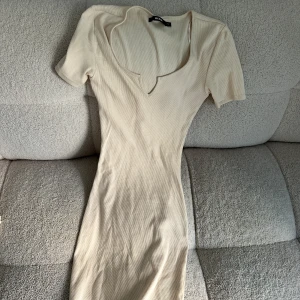 Beige klänning - En beige klänning med korta ärmar och v-ringad hals. Super fin ifrån bikbok