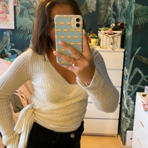 Vit omlottkofta  - Stickad omlottkofta i vitt!  Långa snören att knyta med. Man håller sig väldigt varm. Långa ärmar och croppad i magen. Så söt att ha över en långklänning en sommarkväll! 