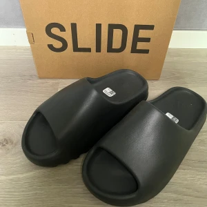 Yeezy Slide “Onyx” - Yeezy slides köpta från Adidas. Oanvända och därför i helt perfekt skick!  Skicka pm om du vill ha någon mer bild eller har en fråga! 