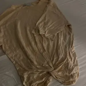 En t-shirt i tunt material med en snurrad knut vid midjan