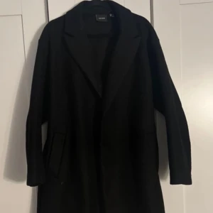 Svart lång kappa  - Säljer denna svarta långa kappan från vero Moda i storleken Xs, men den är stor i storleken. Det vill säga passar alla övriga storlekarna. Den är använd fåtal gånger, men är fortfarande i bra skick. Skriv till mig vid funderingar 💗