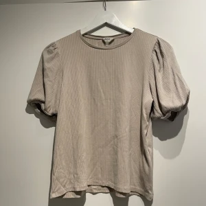 Beige t-shirt  - Beige t-shirt med en liten volang ärm, i storlek S