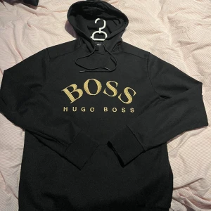 HUGO BOSS HOODIE (Svart / guld) - Size S Nypris 2199 kr Jättesnygg hugoboss tröja i topp skick, svår att få tag på då den inte säljs längre.