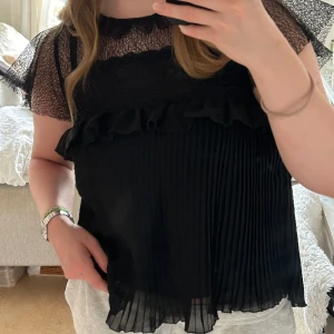 Svart blus  - Svart blus med volanger och spets Storlek S 