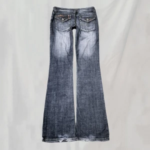 Lågmidjade jeans - Midja: 73 innerben:85 Lågmidjade jeans med stenar på bakfickorna. Sitter bootcut. Uppskattar passa en XS. Nötningar enligt bild men är även del av design. Söm gått upp vid ena fickan enligt bild.Nötta fotändar. Överlag bra vintage skick🤍