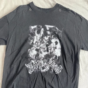 Svart T-shirt med reaper - Använd en gång, köptes i Thailand förra året. De två hålen vid kragen är till för att trä ett halsband igenom de (halsband följer inte med). Det finns inga skador på tröjan.