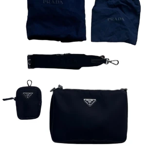 Prada Re-Nylon och Saffiano axelväska - Prada Re-Nylon och Saffiano axelväska i läder. Kommer tillsammans med 2 prada dustbags. Kopia på kvitto finns.   Använts vid få speciella tillfällen och har knappt något slitage.  Säljer då den knappt används.  Köptes 2021 på Smets i Luxemburg. 