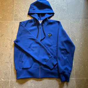 Riktigt skön Comme des Garçons hoodie i färgen blå. Den är som ny helt utan några defekter. Modellen är i L dam men skulle ungefär S/XS herr. Skriv till mig om ni har några funderingar!