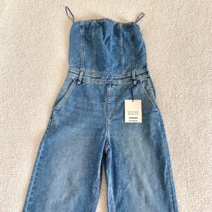 Pull and Bear axelbandslös denim jumpsuit med strass - Otroligt snygg jumpsuit från Pull and Bear med strass diamanter, bälteshällor och fickor. Ny med tags kvar, utan anmärkningar. Storlek S och normal i storleken.
