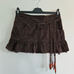 Äkta mocka mini kjol - Äkta mockakjol med beads i snörningen. 36. 