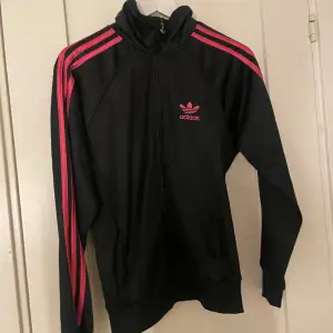 Gammal modell utav adidas jacka med rosa detaljer  Fint skick  Knappt använd Lite stor för mig som är xs/s men snyggt med oversize Nypris:799kr