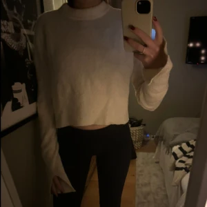 Vit stickad tröja - En stickad tröja med slitsar på ärmarna. Den har två stycken svarta fläckar som man ser på tredje bilden, de är på undersidan av armen så inget man lägger märke till. Tröjan är annars bra skick då den inte använts så mycket.