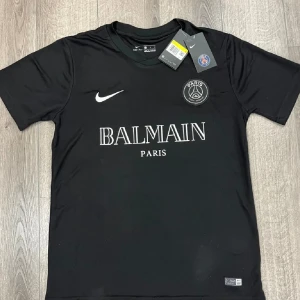 PSG x Balmain t shirt! - Säljer denna t shirten som aldrig är arnvänd! Perfekt nu till sommar 100% äkta mamma köpte den på Nike hem sidan när den var ute där för något år sedan de ser man när man scannar qr koden! Köpt för 749kr säljer billigare för behöver pengar! Hör av er