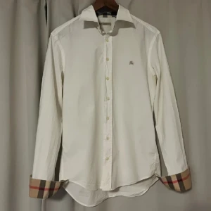 Burrberry skjorta - Säljer min Burberry skjorta i storlek M och färgen vit. Skick 10/10 inga defekter. Perfekt till en sommar ghäda. Kan sänka pris vid snabb affär tar även byten.