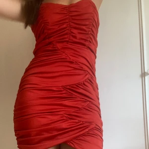 Röd kort klänning - En röd kort klänning med åtsittande passform. Klänningen har rynkade detaljer och tunna axelband. Aldrig använt 