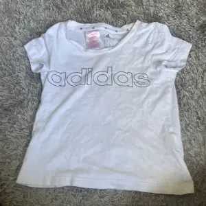 En vit t-shirt från Adidas med korta ärmar och Adidas-logotypen tryckt på framsidan. T-shirten är i storlek 7-8 år (128 cm).