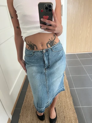 Lågmidjad jeanskjol - Vintage lågmidjad jeanskjol med strass (några saknas), passar mig med midjemått 24/25