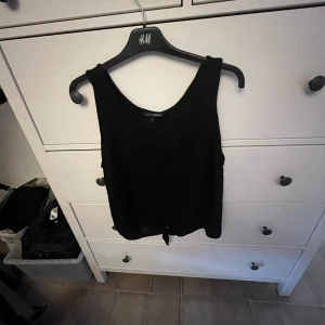 Svart topp från KappAhl - En svart topp från KappAhl i storlek L. Toppen har en enkel design med knappar framtill.