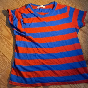 Hej! Jag säljer en t-shirt som är röd och blå från H&M. Den har ett pyttelitet hål på magen. Det är storlek 122-128/6-8 år.  - En mjuk och  fin färgglad t-shirt.