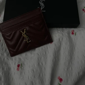 YSL korthållare - En vinröd korthållare jag köpte här på Plick för inte så längesedan, ägaren var inte säker på varans äkthetsintyg. Box medföljer!