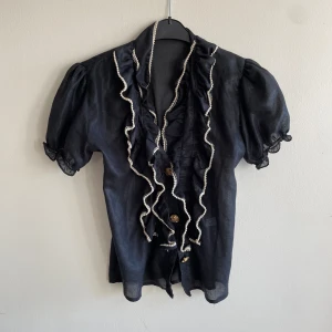 Söt blus - Söt svart blus med volanger och guld knappt 