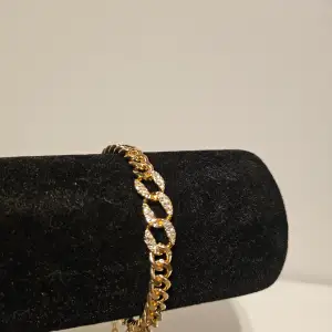 Guldfärgat armband med en bit som glittrar, aldrig använt